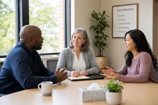 Mediator leading a peaceful discussion between two neighbors in a bright office in the Yvelines, with natural light and calm atmosphere.